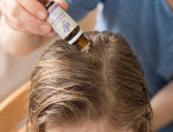 Maman qui applique une huile essentielle sur les cheveux de son enfant pour lutter contre les poux