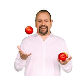 Homme barbu et souriant en chemise blanche jonglant avec trois pommes rouges.