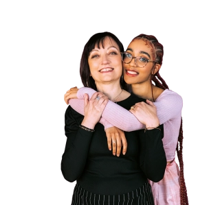 Deux femmes souriantes se serrent dans les bras. L'une, aux tresses et lunettes, étreint l'autre, aux cheveux longs noirs.